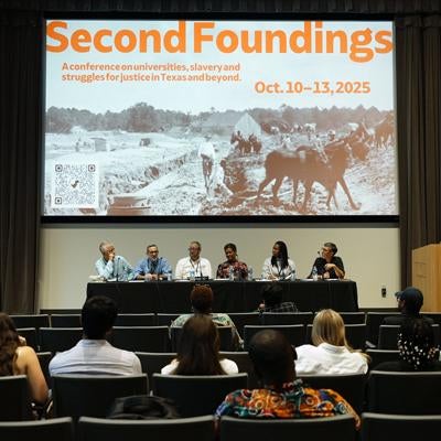 panelists in auditorium with screen text Second Foundings: A conference on universities, slavery and struggles for justice in Texas and beyond. Oct.10-13, 2025