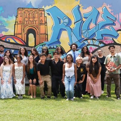 group of RISE students in front of Rice graffiti wall