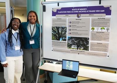 two students next to a white board presentation